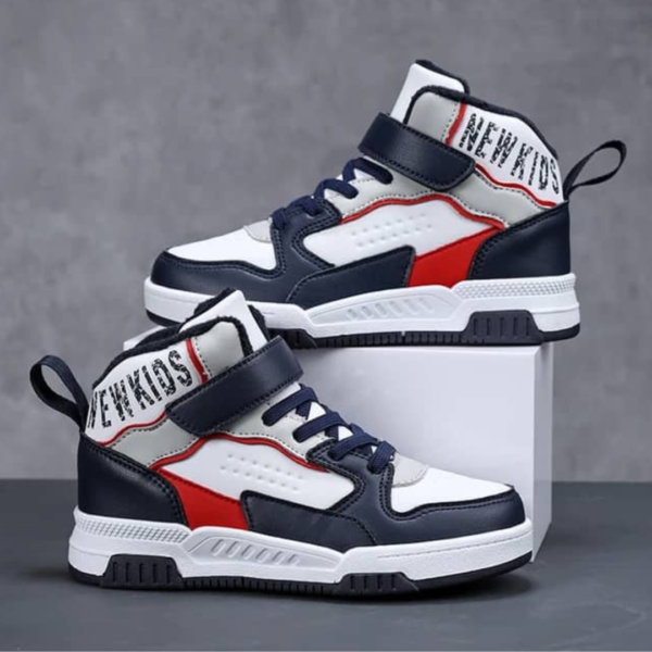 Kids' high-top athletic sneakers in navy blue, red, and white with velcro strap and lace-up closure, worn by a child. The sneakers have a stylish design with color-blocking details, providing both ankle support and a trendy look.